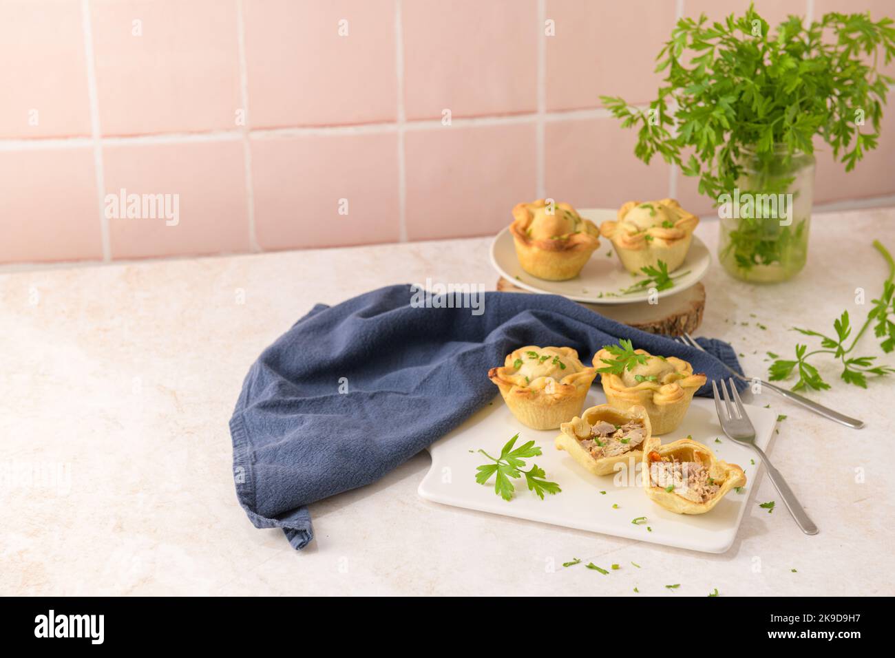 Chicken pies and parsley leaves on white ceramic dishes in a kitchen