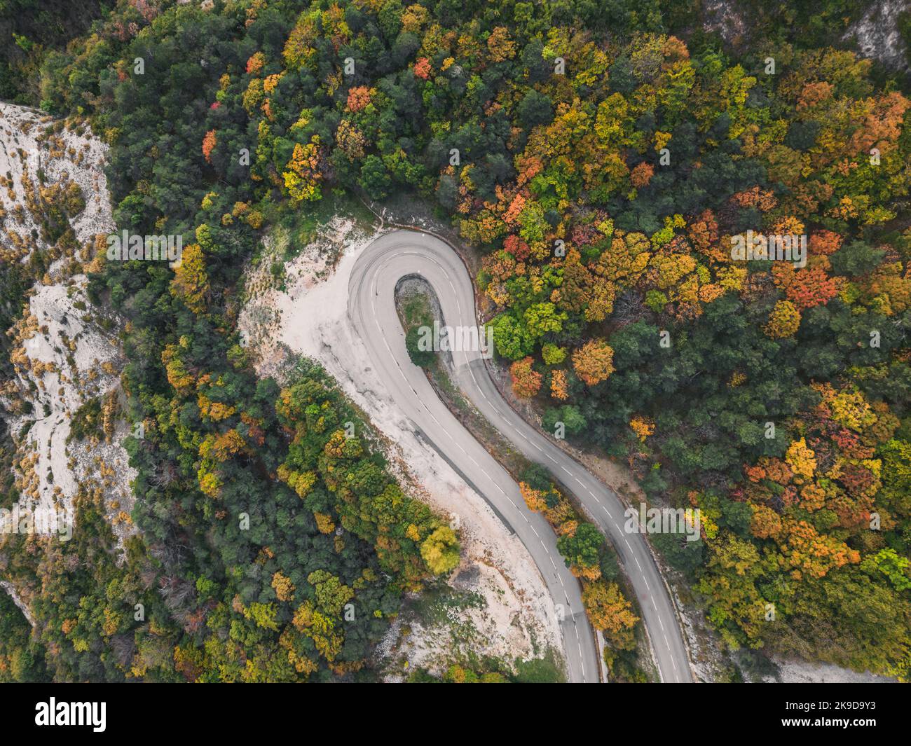 Aerial view of a winding road from a high mountain pass through a dense ...
