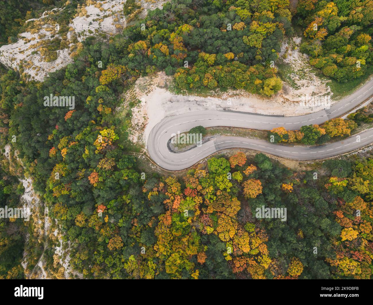 Aerial view of a winding road from a high mountain pass through a dense ...