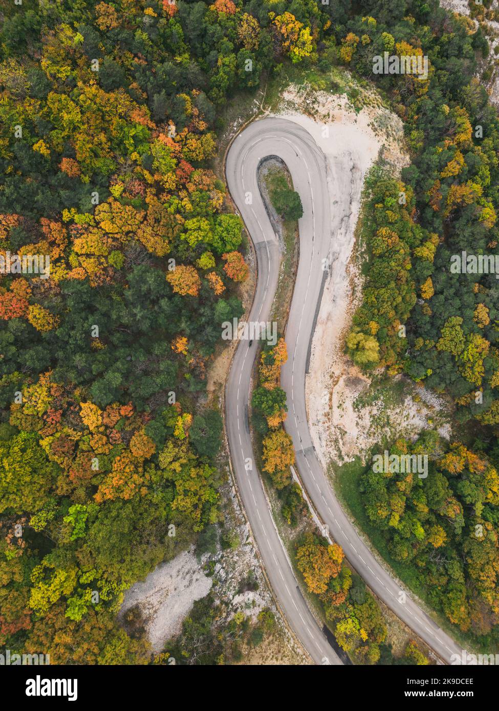 Aerial view of a winding road from a high mountain pass through a dense ...