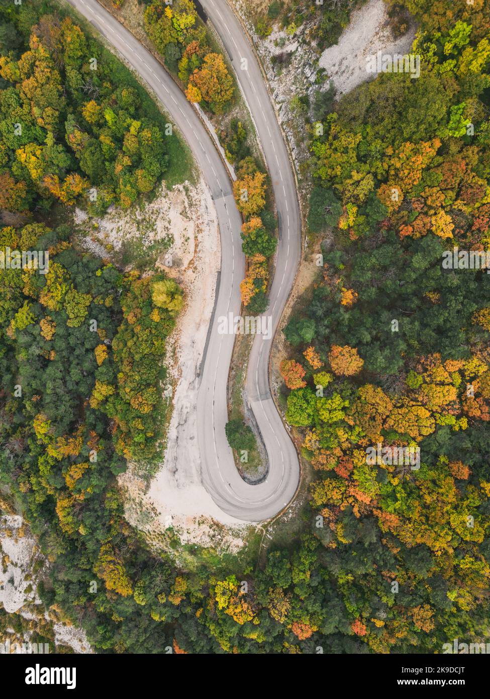 Aerial view of a winding road from a high mountain pass through a dense ...
