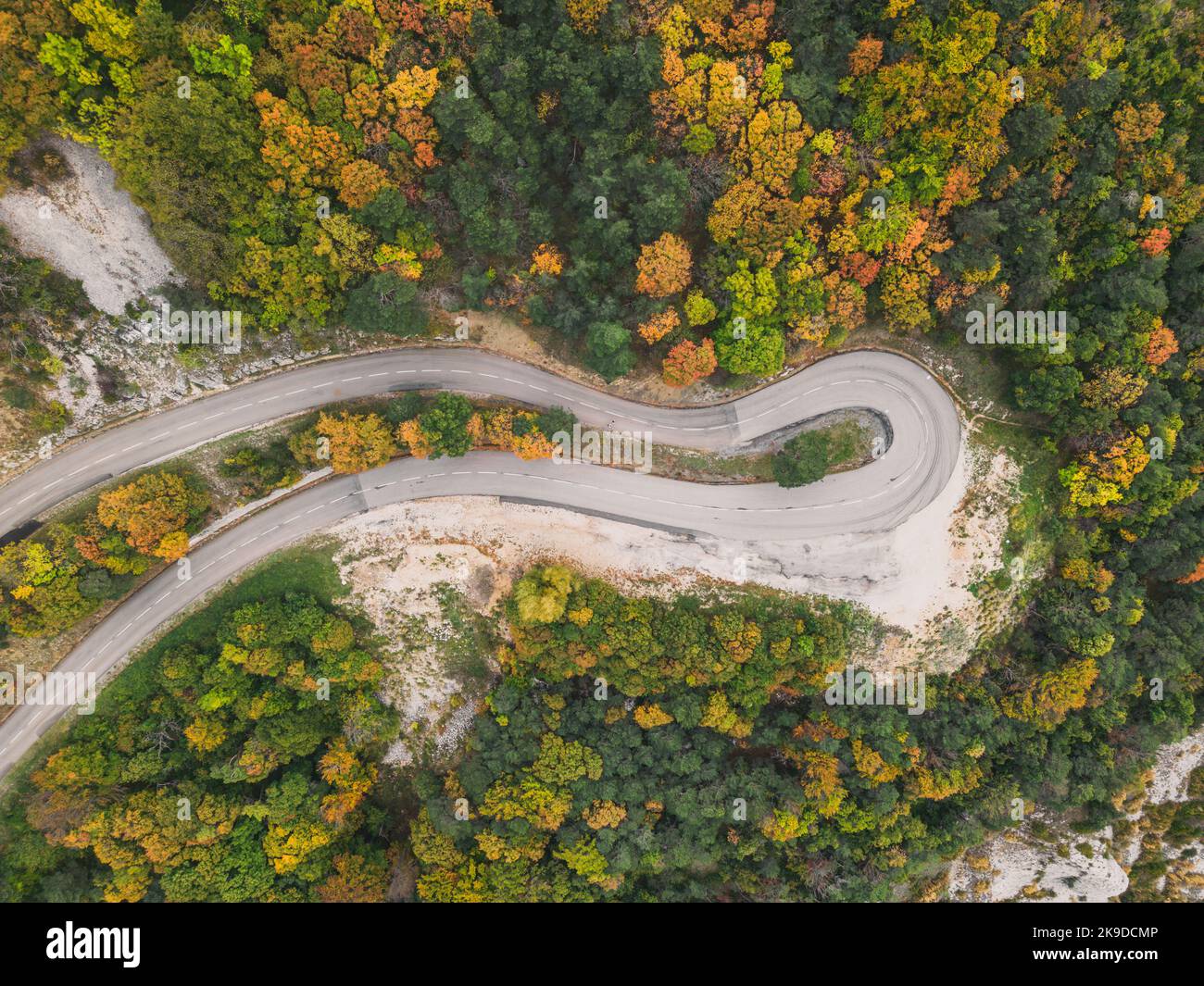 Aerial view of a winding road from a high mountain pass through a dense ...