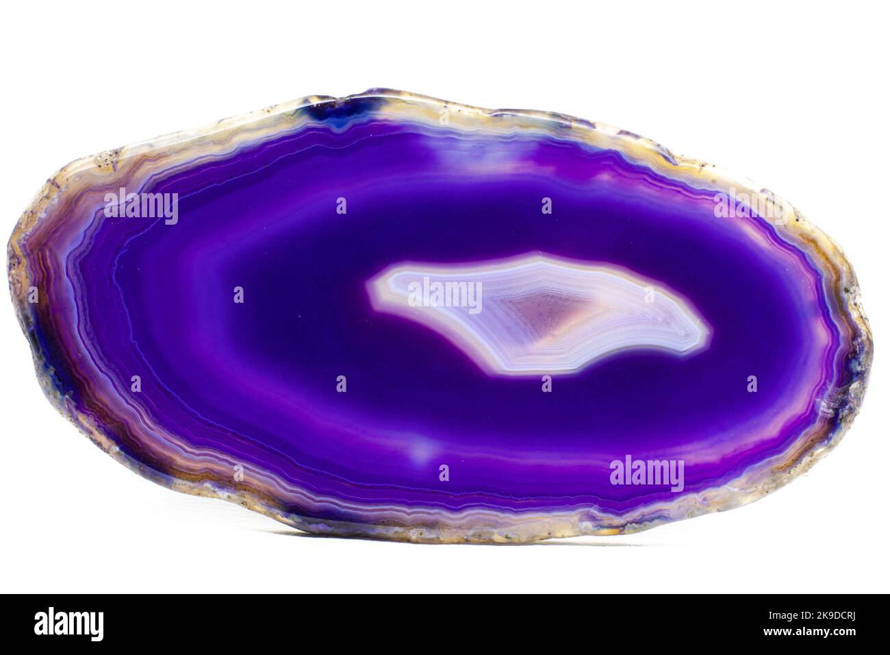 Purple and Blue agate slice crystal , banded chalcedony stone isolated on a white background surface with lots of detail. Copy space Stock Photo