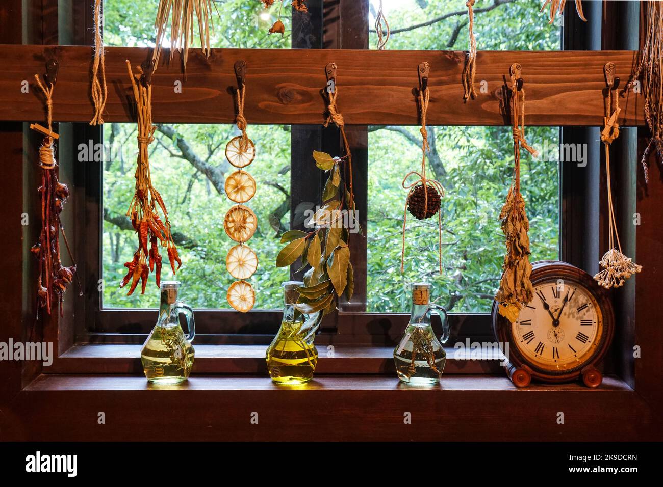 Hanging dried herbs next to various infused oils Stock Photo