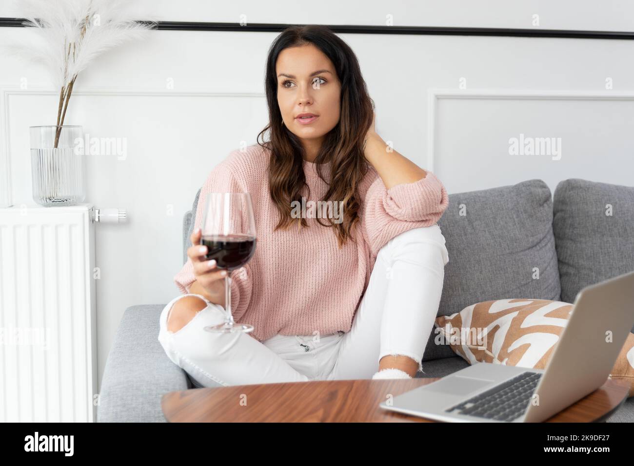 Woman sitting on couch, resting with glass of red wine Stock Photo