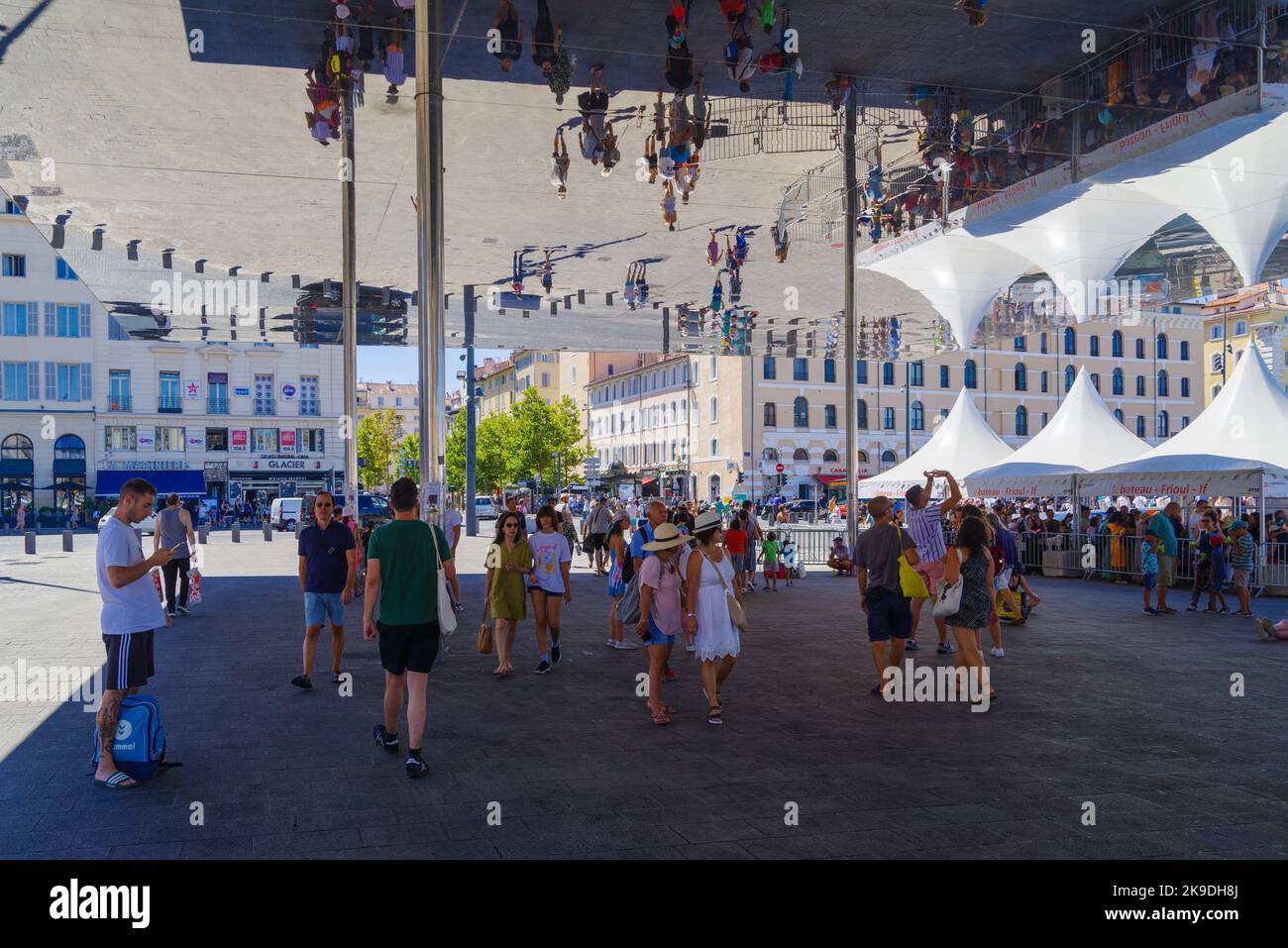 MARSEILLE, FRANCE - AUGUST 2, 2022: People under a mirror canopy in the old harbor (vieux port). It has been the natural harbour of the city since ant Stock Photo