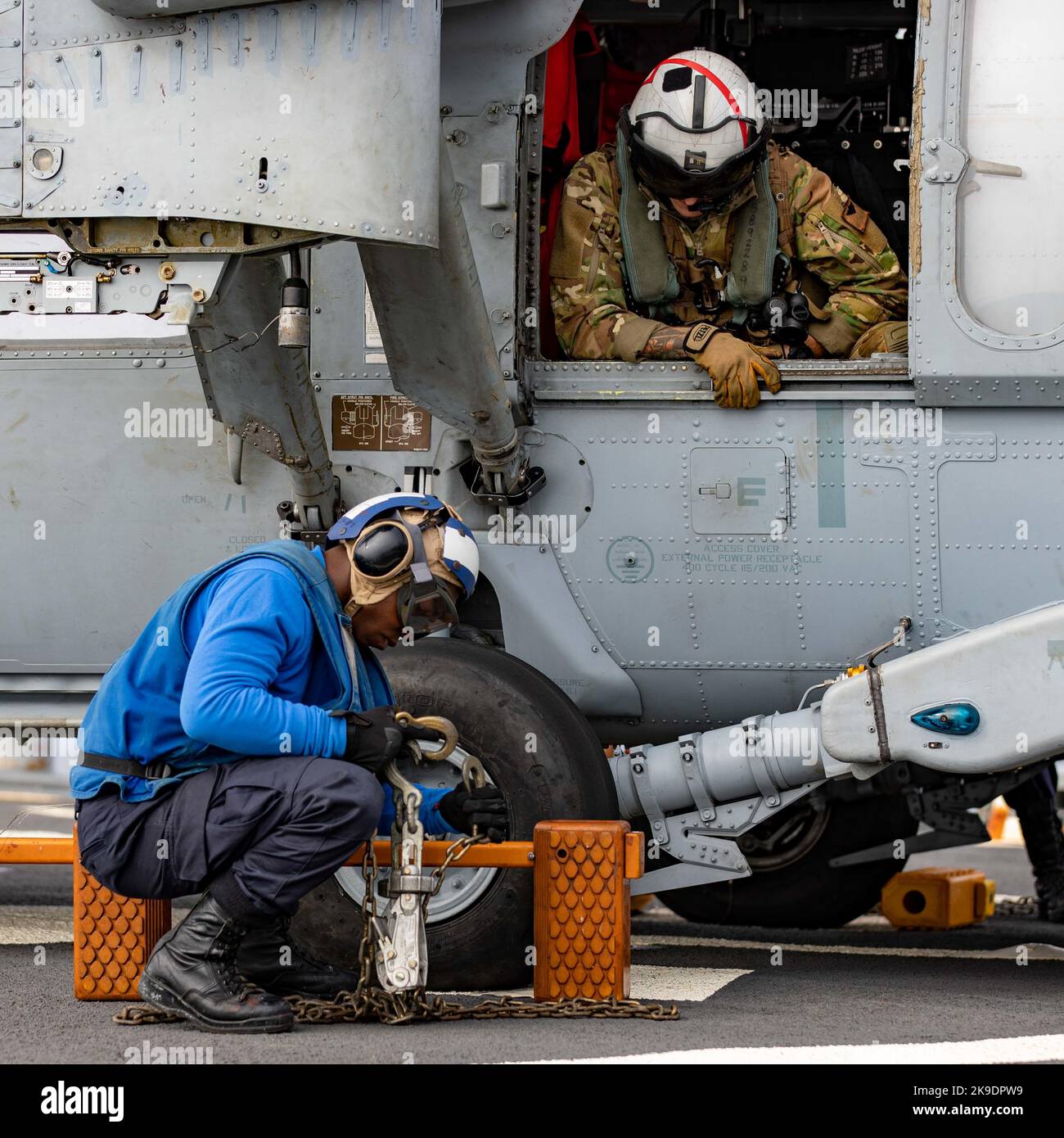 Naval Air Crewman 1st Class Bobby Nilson, right, assigned to the “Tridents” of Helicopter Sea Combat Squadron (HSC) 9, watches as Seaman Joshua Whitaker, assigned to the Arleigh Burke-class guided-missile destroyer USS Ramage (DDG 61), removes chocks and chains an MH-60S Sea Hawk helicopter, attached to the “Tridents”, during flight operations as part of the Gerald R. Ford Carrier Strike Group, Oct. 25, 2022. The first-in-class aircraft carrier USS Gerald R. Ford (CVN 78) is on its inaugural deployment conducting training and operations alongside NATO Allies and partners to enhance integration Stock Photo