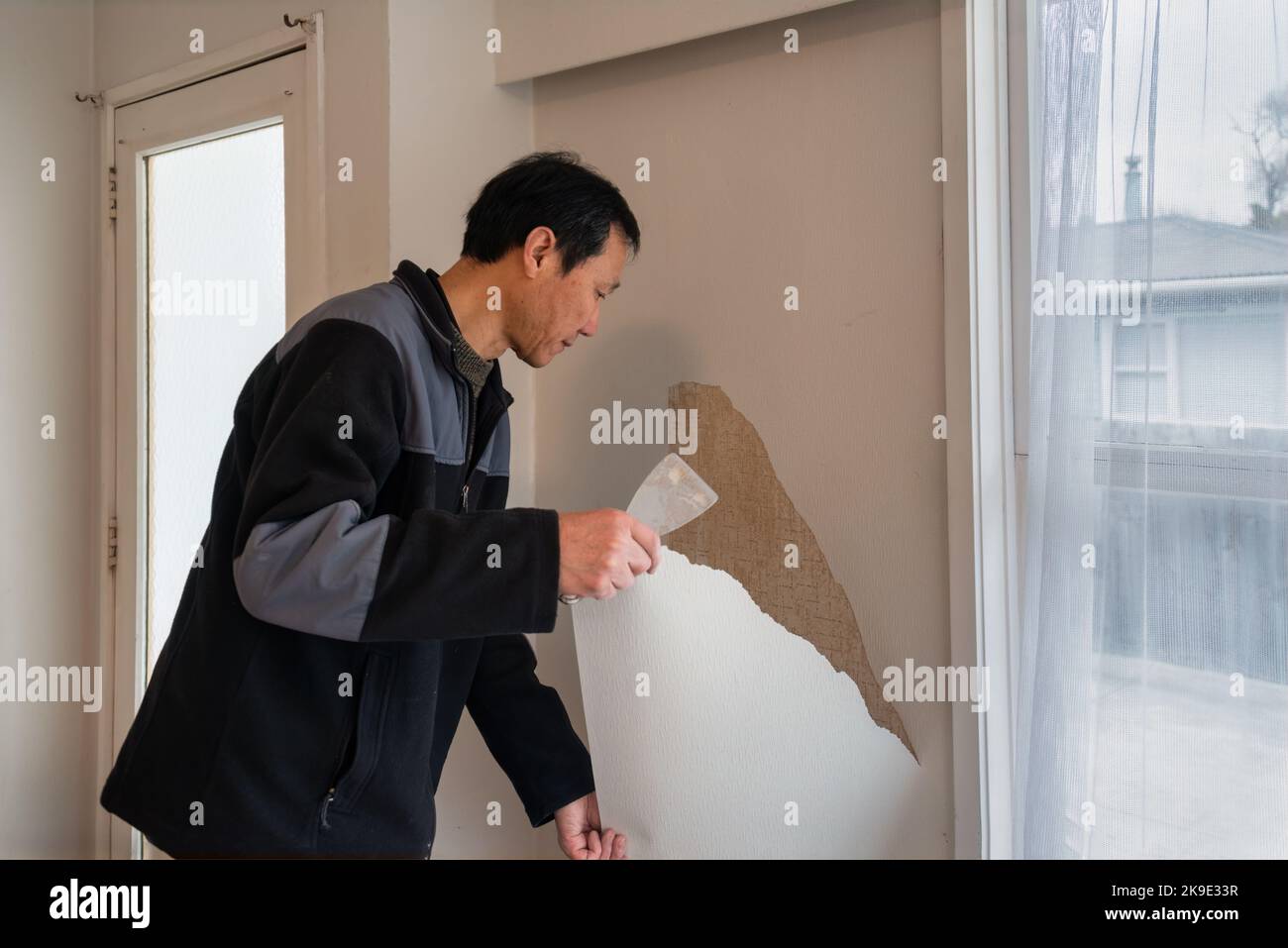 Man removing wallpaper inside an old house. Home interior do it