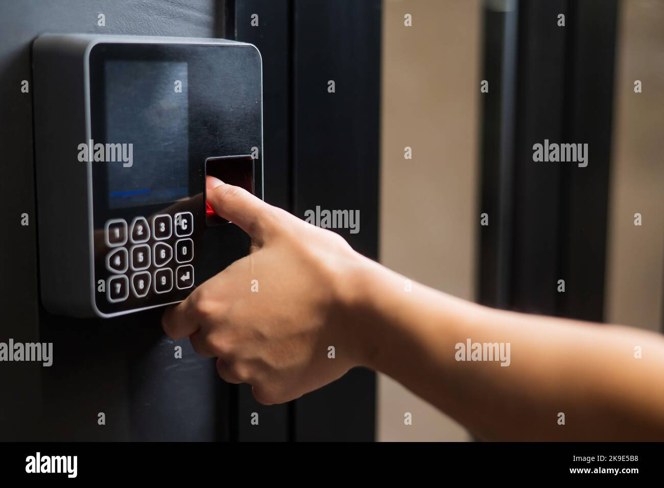 A woman opens the door with her fingerprint. Modern keyless entry lock.  Stock Photo