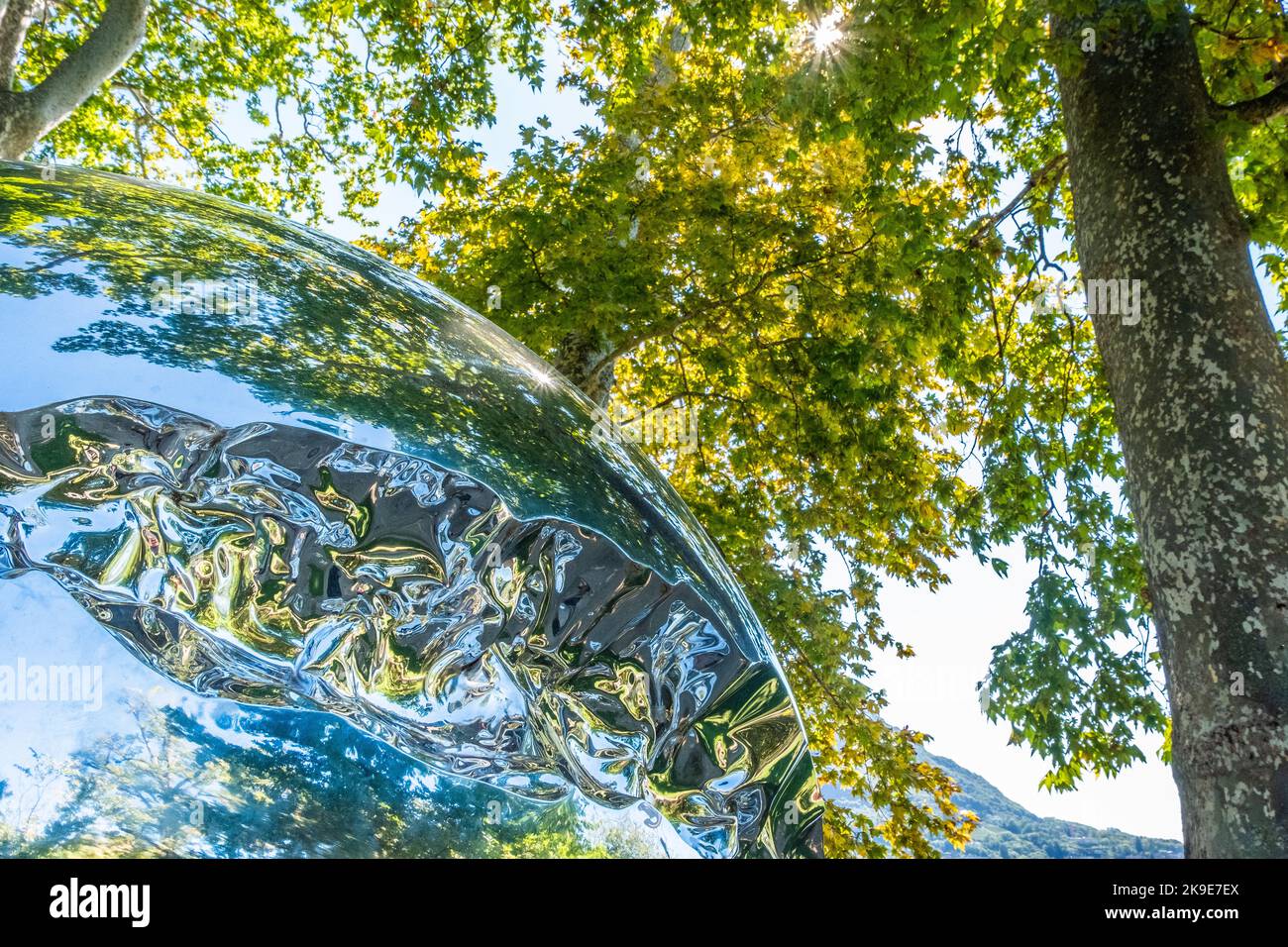 Chrome sphere reflecting trees and blue sky. Stock Photo