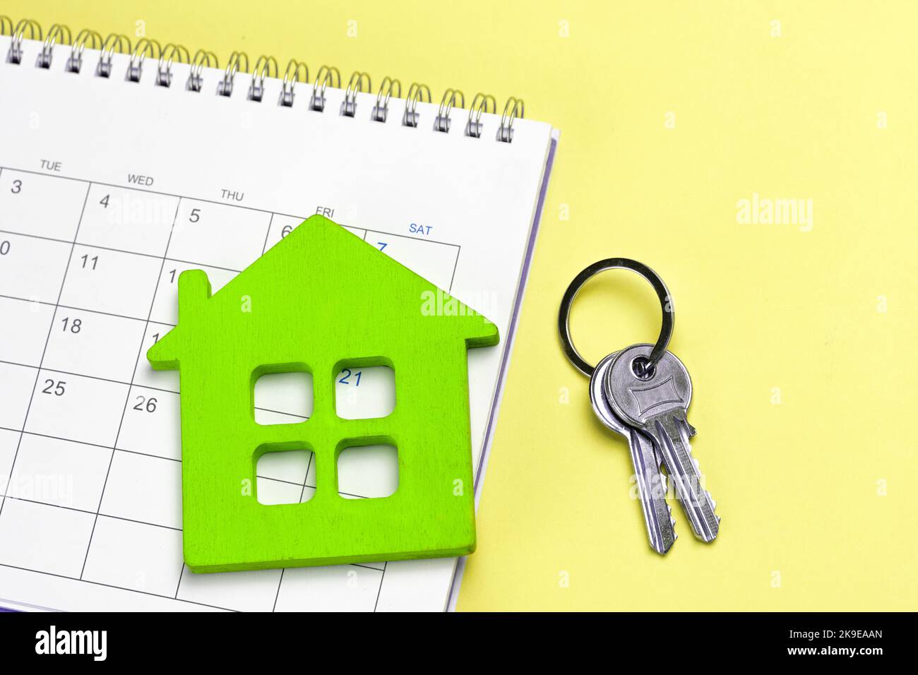 Green house with calendar and keys on yellow background. Stock Photo