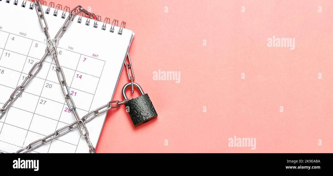 Calendar is wrapped in a chain and closed with a padlock. Red background. Template Copy space for text. mock-up Stock Photo