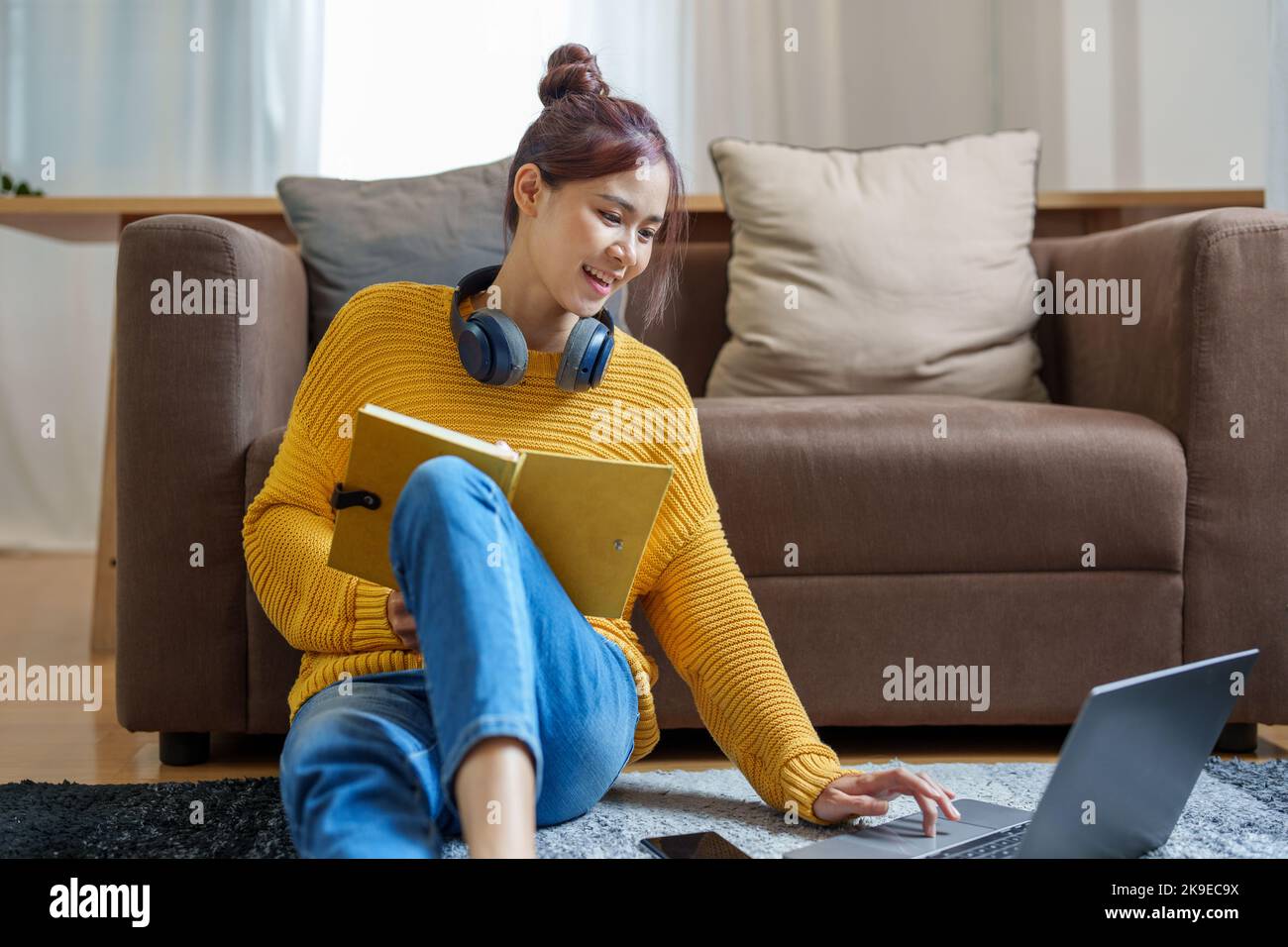 Portrait of a young Asian woman using a computer on the sofa Stock ...