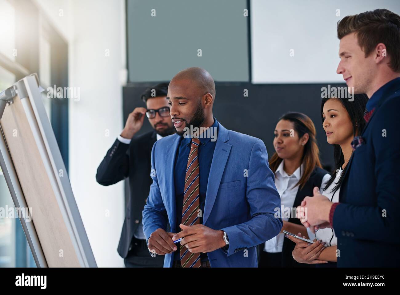 Hes pitch is impressing everyone. a young businessman giving a demonstration on a white board to his colleagues in a modern office. Stock Photo