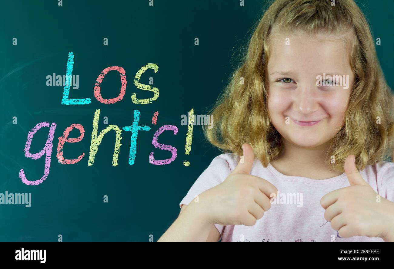School child in front of a blackboard with the German inscription: Los geht's( Let's go) Stock Photo
