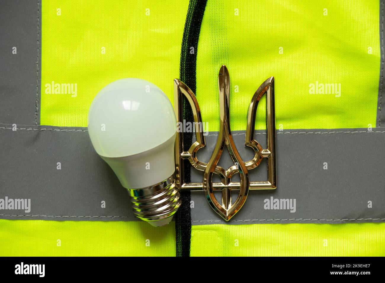 LED lamp and coat of arms of Ukraine lie on a reflective vest, Ukraine without light, energy crisis, war Stock Photo