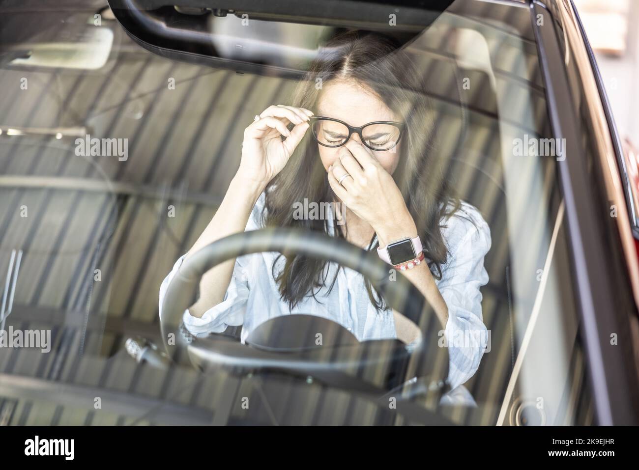 Tired female driver with glasses, needs a break to continue driving the car. Stock Photo
