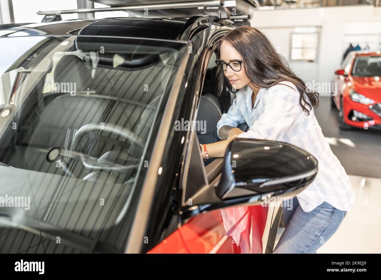 A young customer takes advantage of the inspection of a new car in the store. Stock Photo