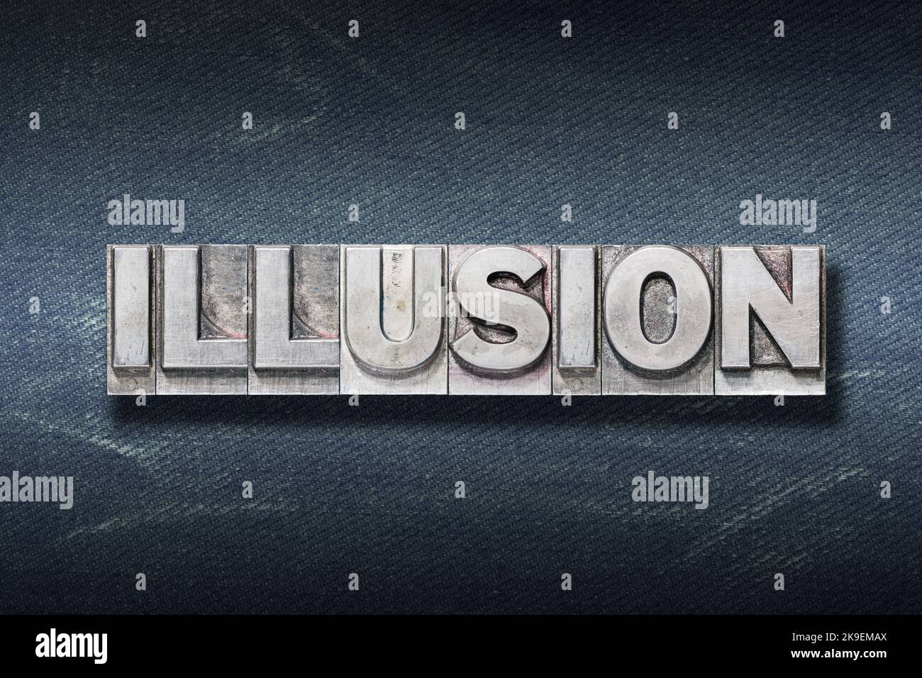 illusion word made from metallic letterpress on dark jeans background Stock Photo