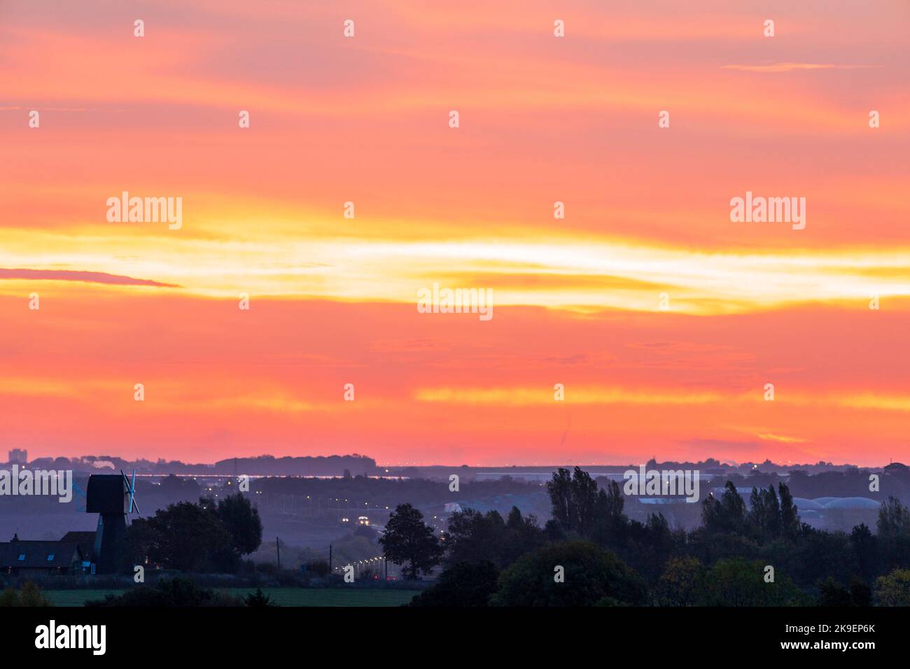 The dawn sky in an orange and red vivid sky with cloud over a landscape ...