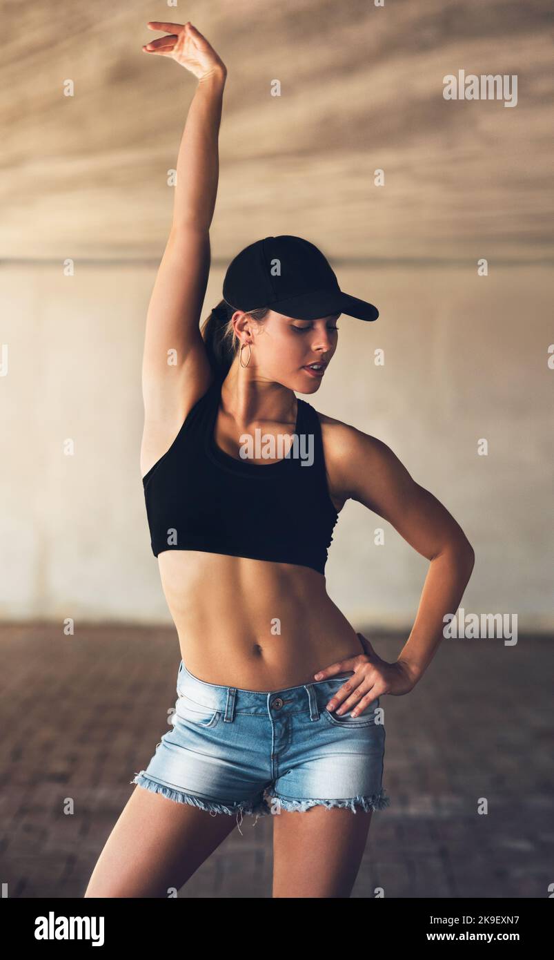 She moves to the beat of her own drum. an attractive young female street dancer posing with her arm raised while practising out in the city. Stock Photo