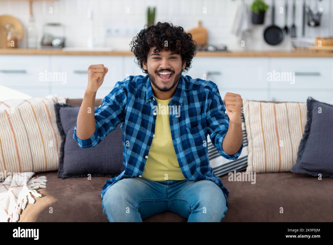 Portrait of happy Indian man overjoyed with good news. Smiling male with curly hair showing yes gesture Stock Photo