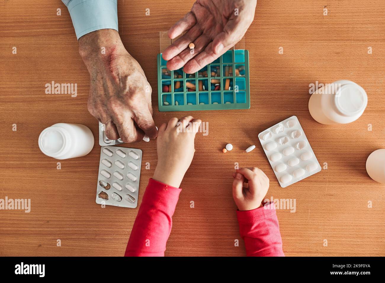 Grandchild helping grandfather to organize medication into pill