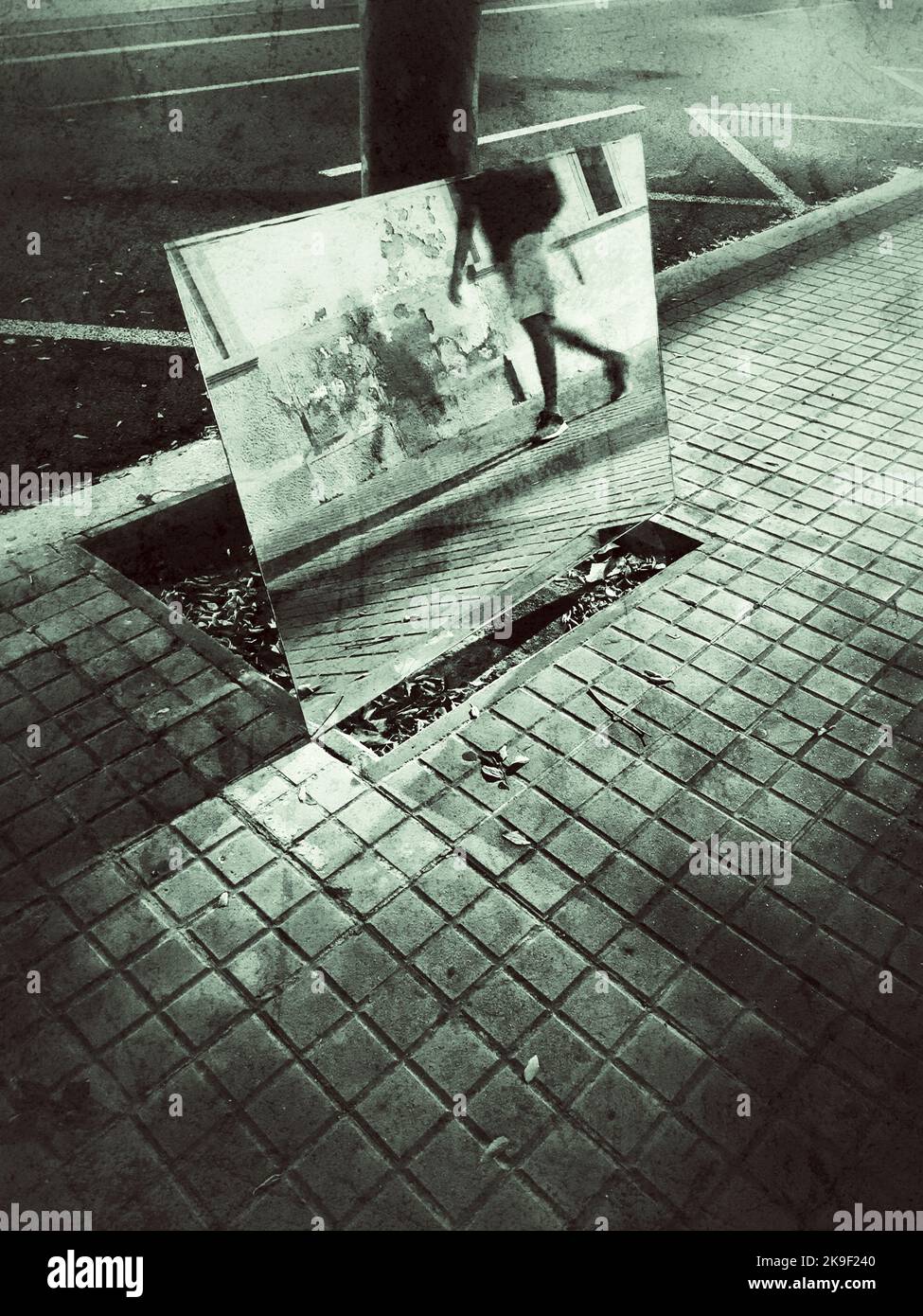 A man is reflected on a mirror at night while he is walking in a street