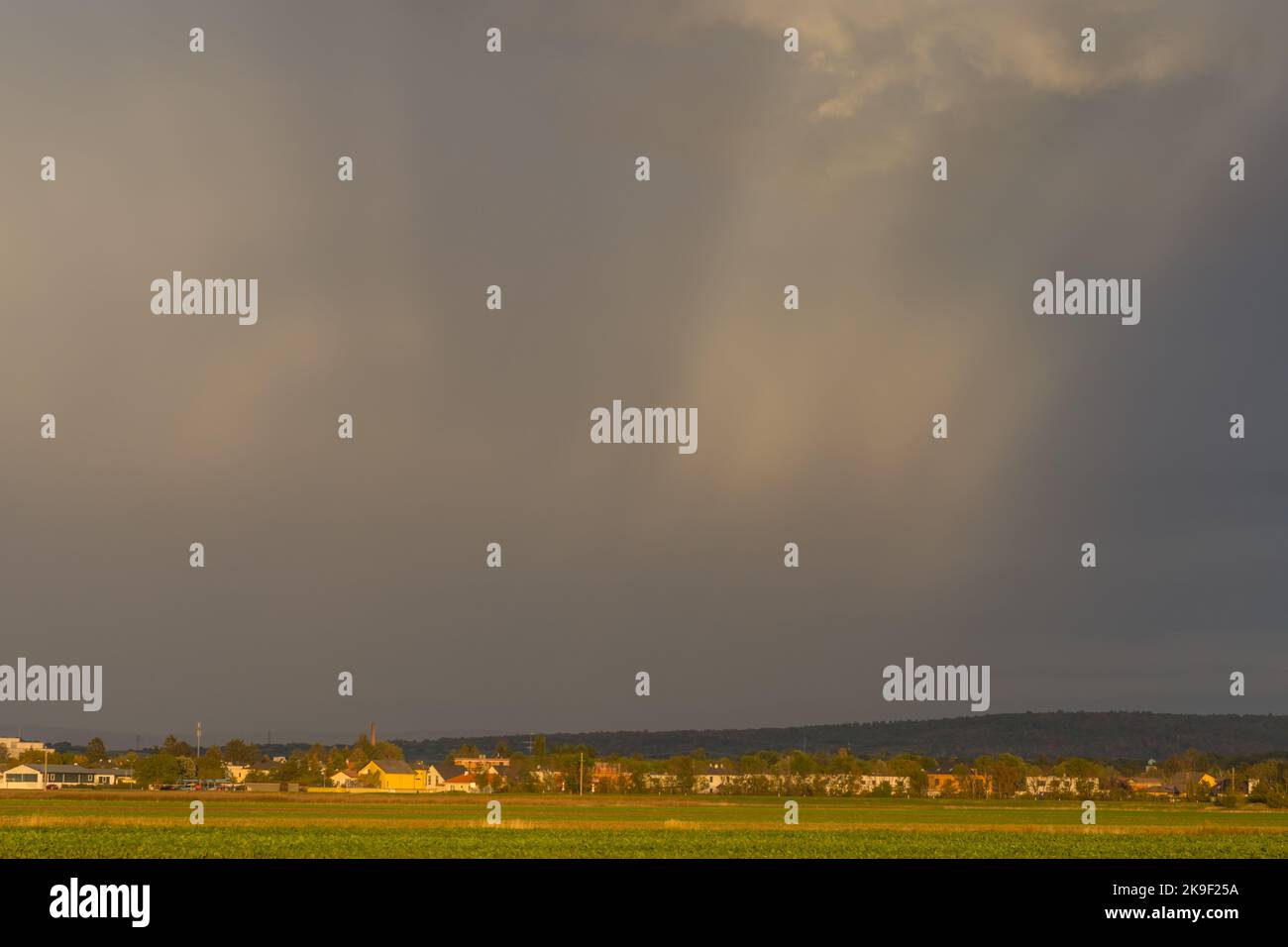 flat landscape with houses and sunrays between dense rainclouds Stock Photo