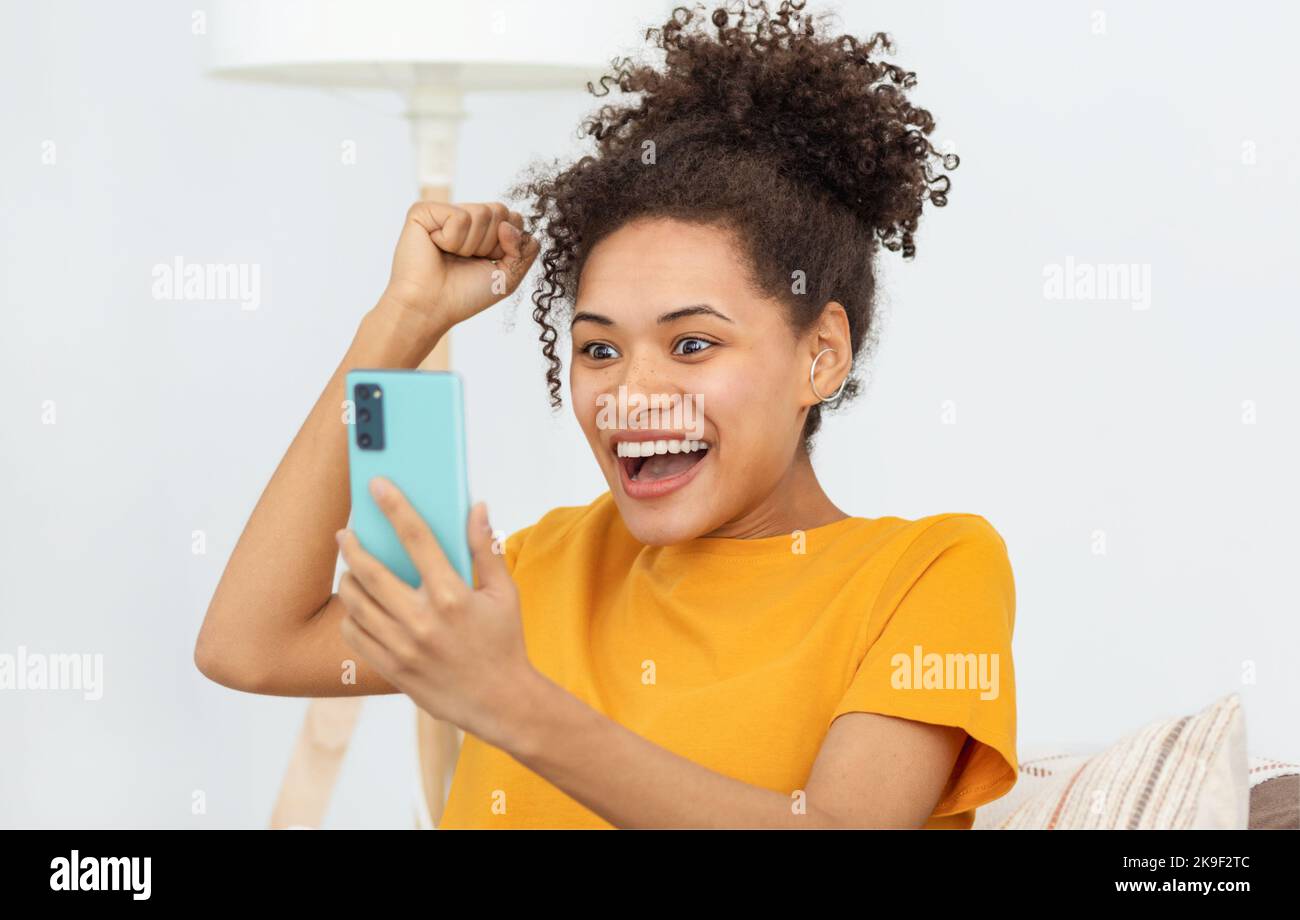 Excited young woman using mobile phone shopping online Stock Photo