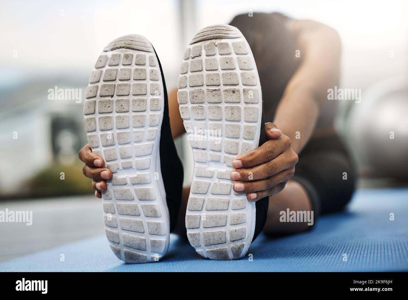 The only bad workout is the one that didnt happen. an attractive young woman sitting with her head down doing stretching exercises on her gym mat at Stock Photo