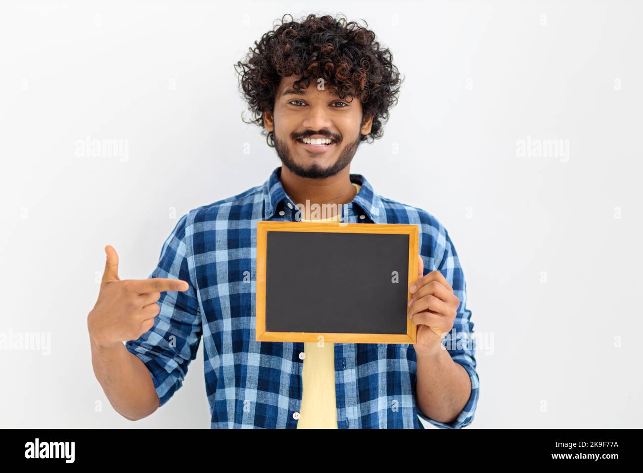 Portrait of young Asian man with chalkboard on white background. Male with curly hair holding a blank chalk board Stock Photo