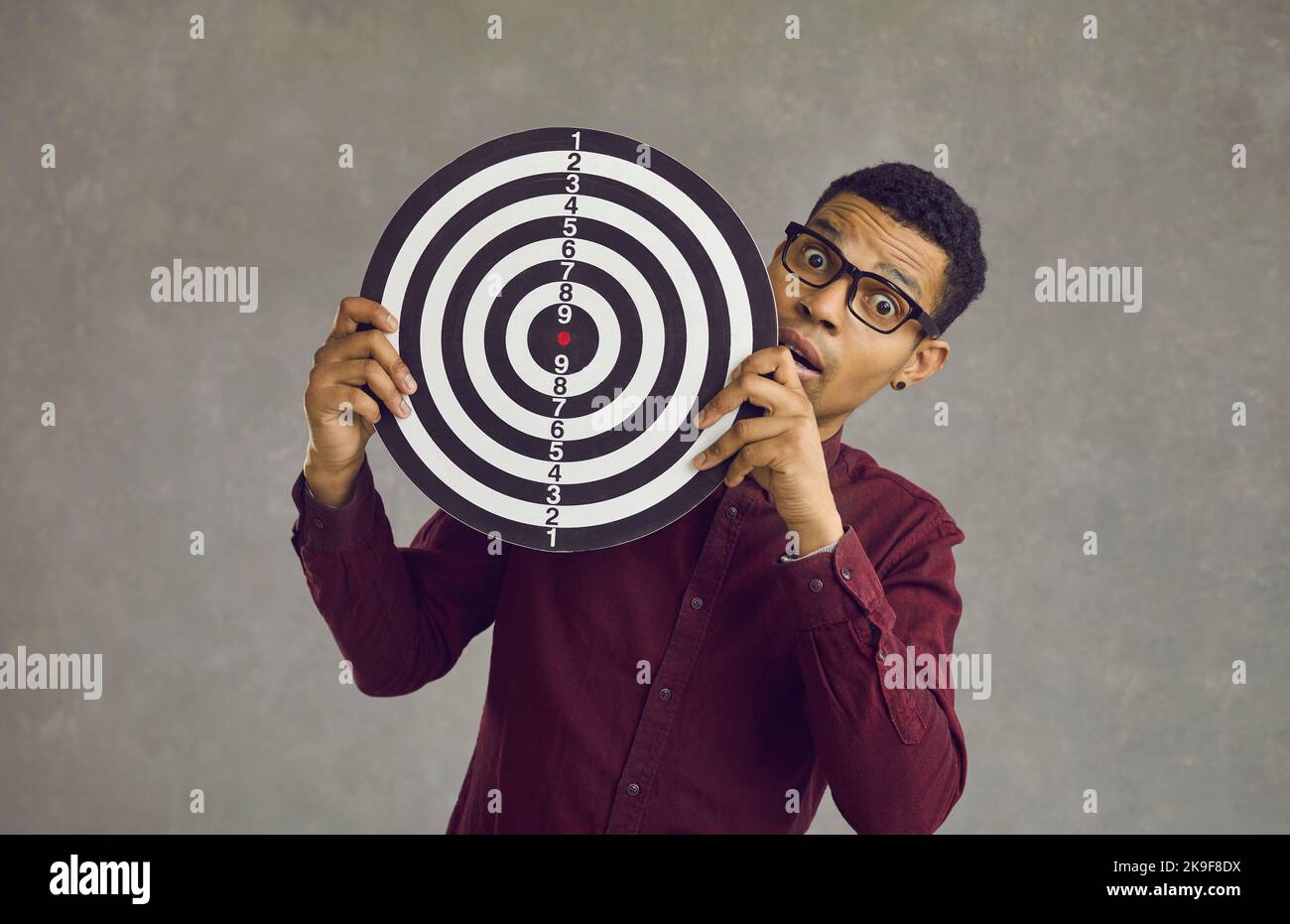 Young african american shocked man with dartboard over grey studio wall Stock Photo