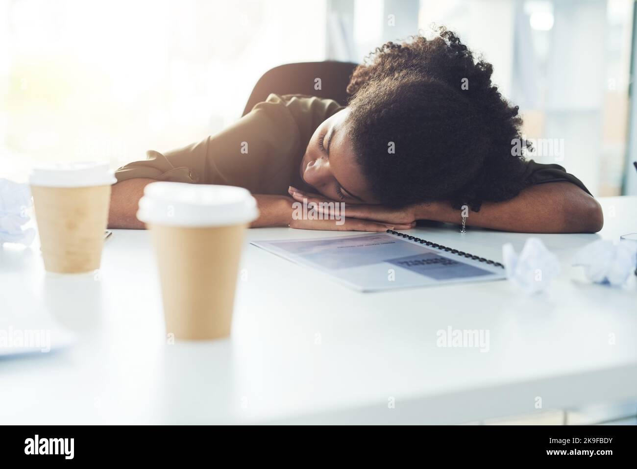 Just a quick nap to awaken the best of ideas. a young businesswoman sleeping with her head down on her office desk. Stock Photo