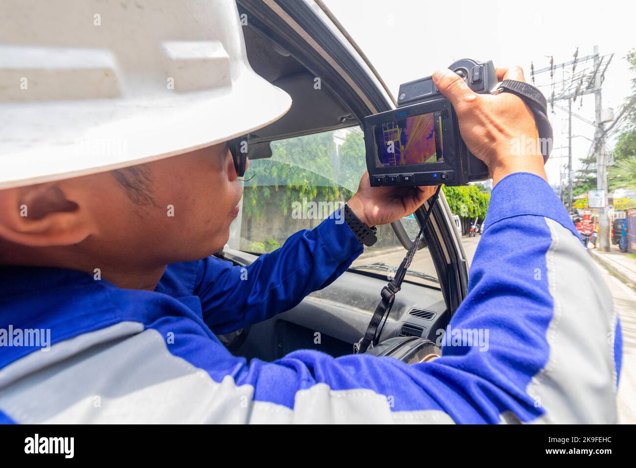 A Filipino electric utility worker using a thermal camera to check a