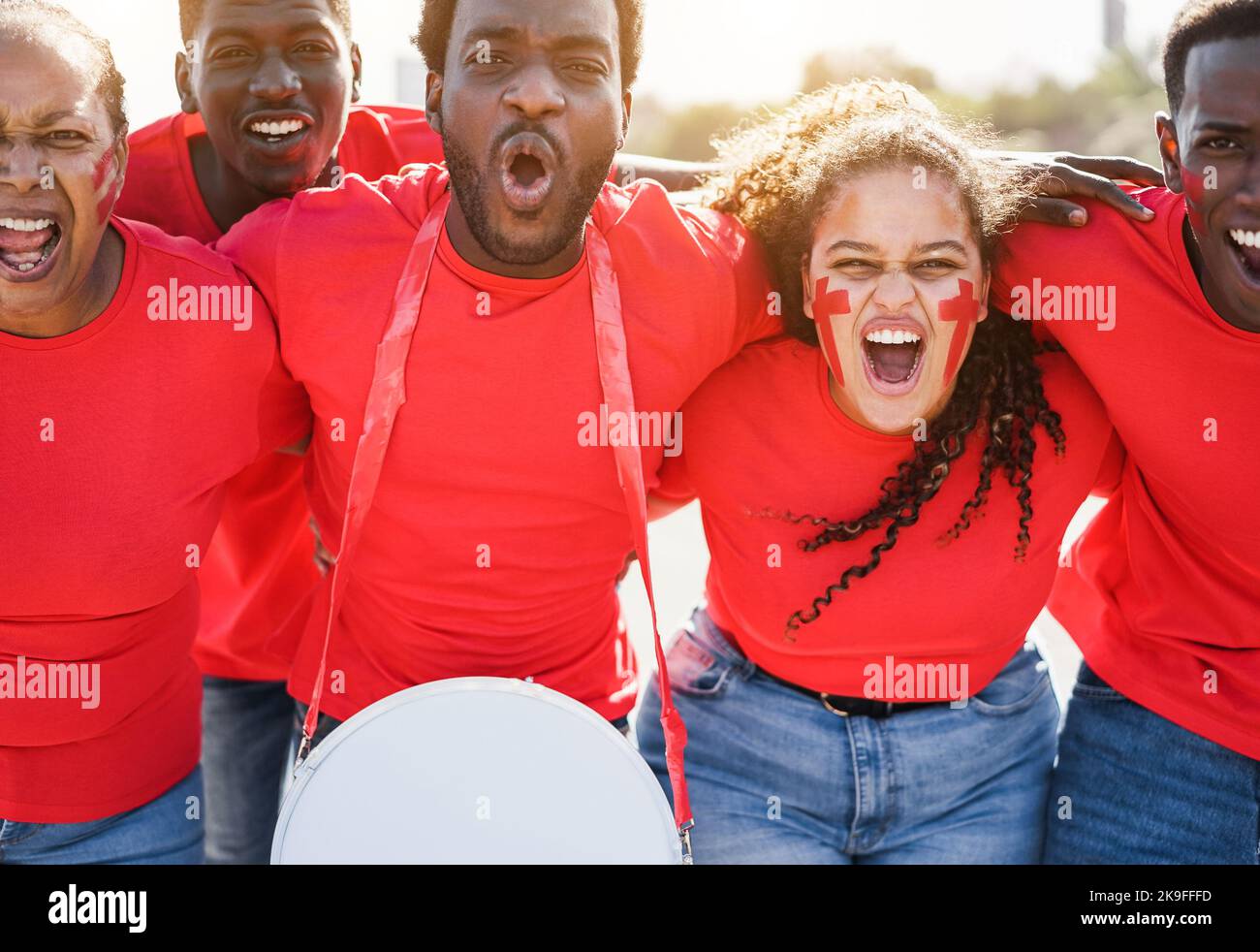 African red sport fans screaming while supporting their team - Football supporters having fun at competition event - Focus on curvy girl face Stock Photo