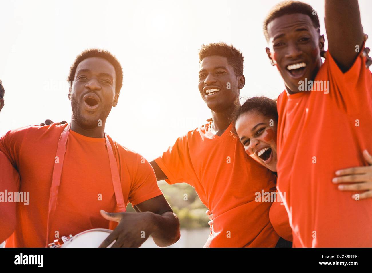 Orange sport fans screaming while supporting their team - Football supporters having fun at competition event - Soft focus on center guy face Stock Photo