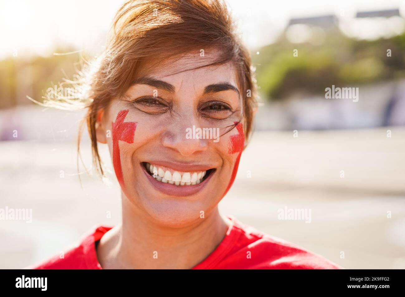 Red mature sport fan laughing out of the stadium before football match - Focus on left eye Stock Photo