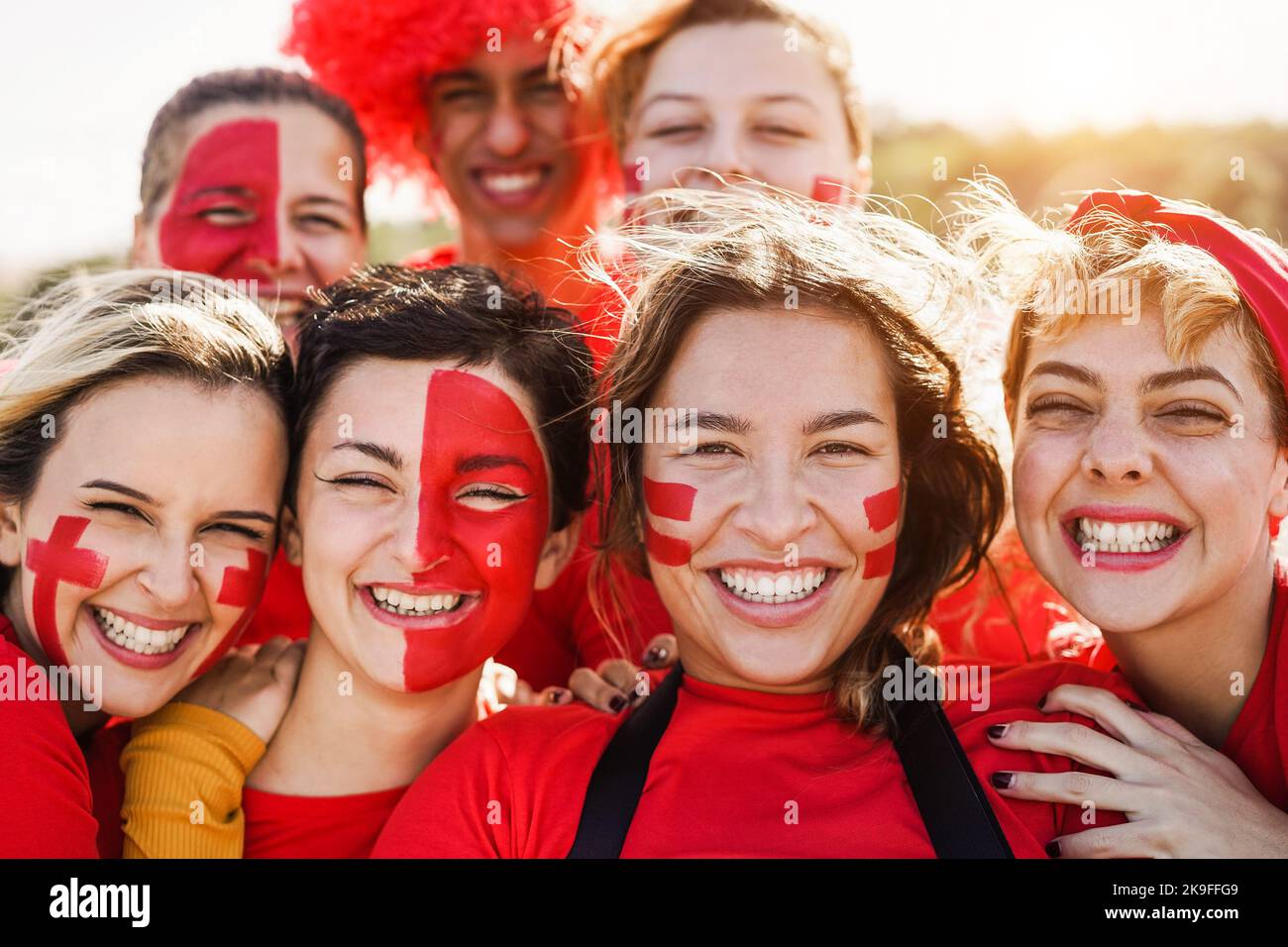 Red sport fans screaming while supporting their team - Football supporters having fun at competition event - Focus on second girl on right Stock Photo
