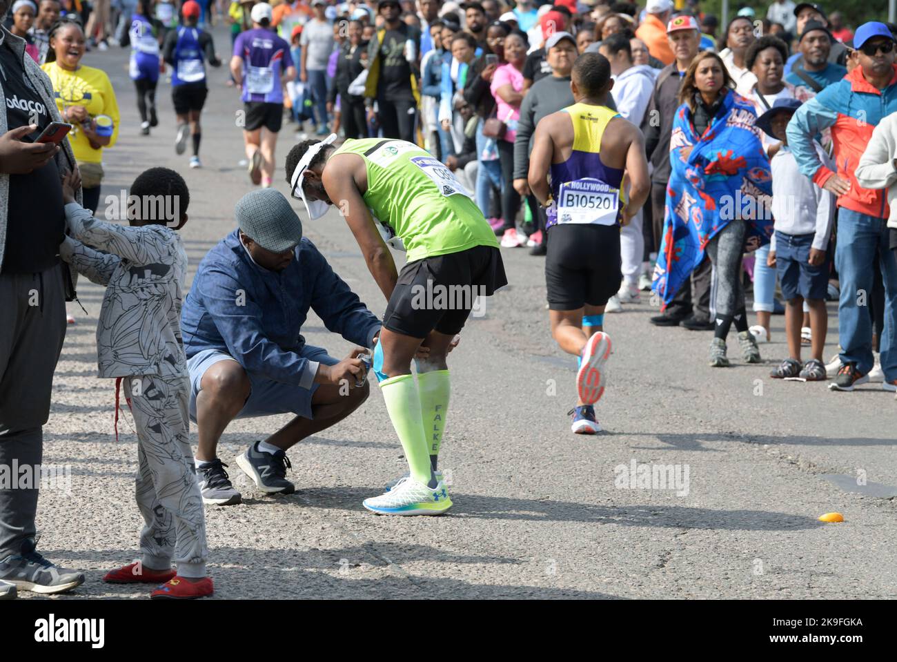 Adult male runner in pain, first aid help, 95th Comrades Marathon 2022, extreme sport event, human drama, ultimate human race, Durban, South Africa Stock Photo