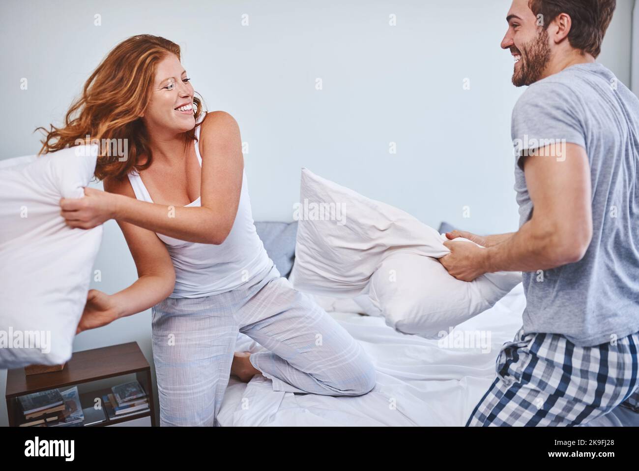 Theyre in a playful mood this morning. a couple having a pillow fight at home. Stock Photo