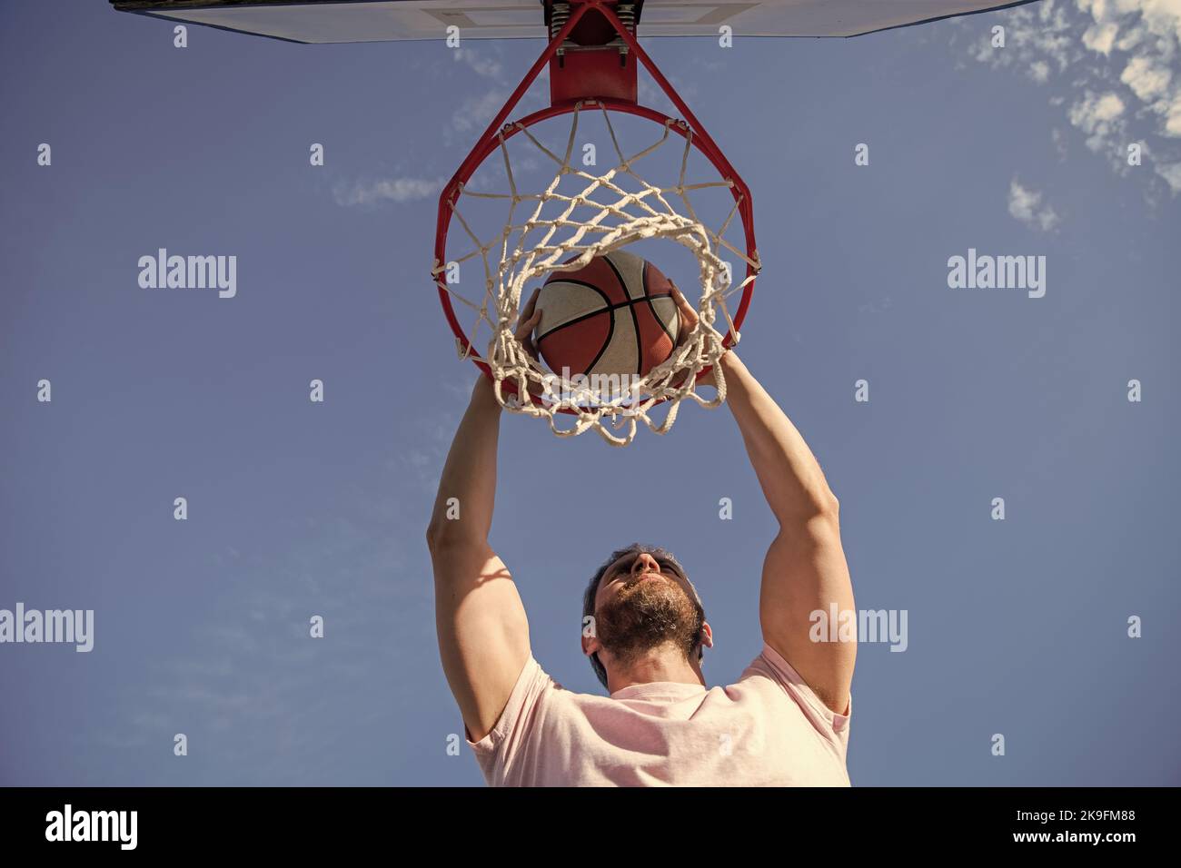 player dunking basketball ball through net ring with hands, sport motivation Stock Photo