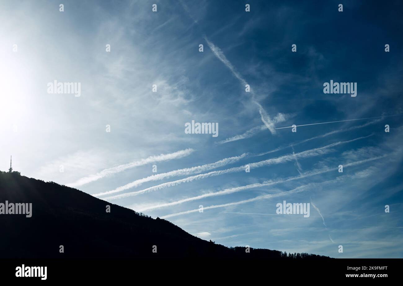 Massive airliner contrails, some new, some old, in the sky above Gaisberg, a mountain near the city of Salzburg, Austria, Europe. Air pollution. Stock Photo