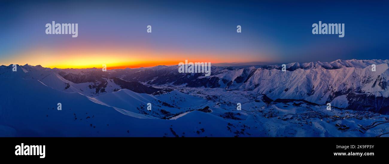 Wide aerial panorama of snowy mountain ridge on winter sunrise ...