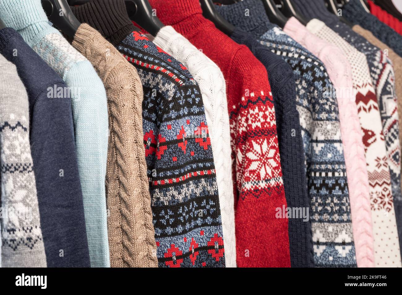 Various vintage turtleneck sweaters and pullovers on hanger rack in a used goods store. Thrifting and sustainability in clothing concept Stock Photo