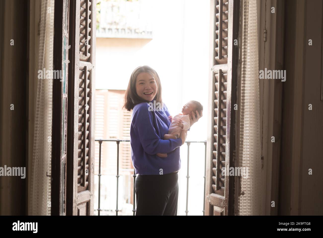 lifestyle shot on young and happy Asian Chinese woman holding tenderly her adorable newborn baby girl in her arms in mother and daughter love and care Stock Photo