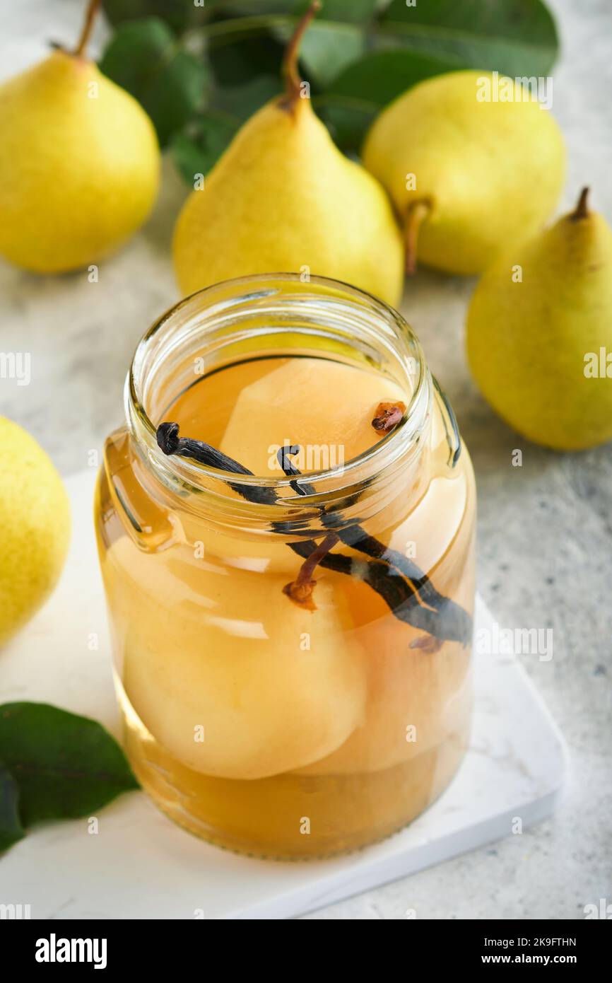 Canned pear compote with vanillin. Pear compote. Homemade delicious canned pear compote in glass jars at home on a light background. Homemade food. Sp Stock Photo