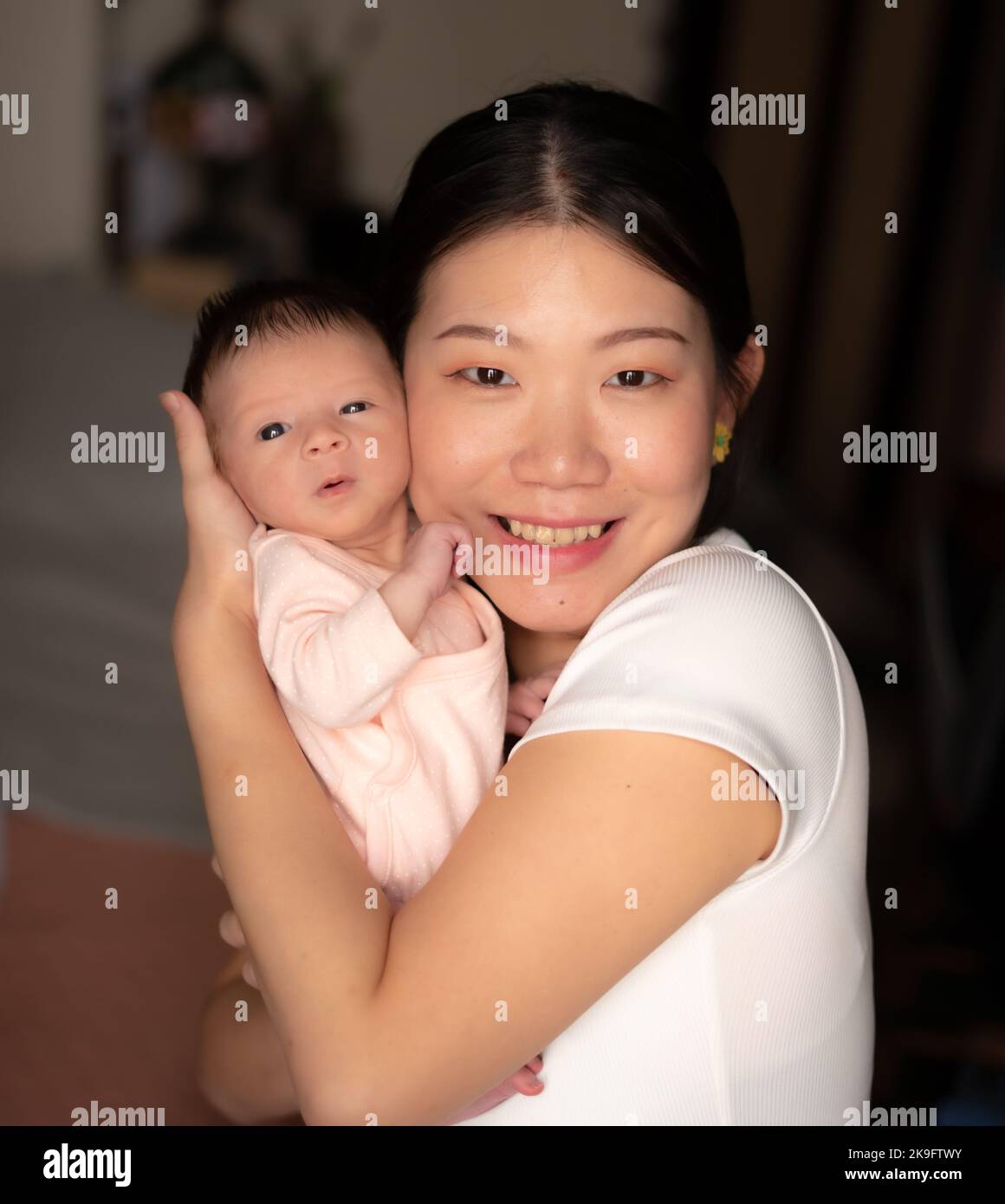 lifestyle shot on young and happy Asian Chinese woman holding tenderly her adorable newborn baby girl in her arms in mother and daughter love and care Stock Photo