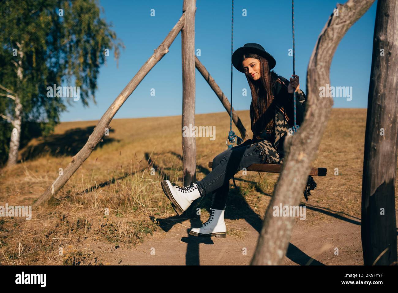 Young beautiful woman rides on a swing in the countryside Stock Photo