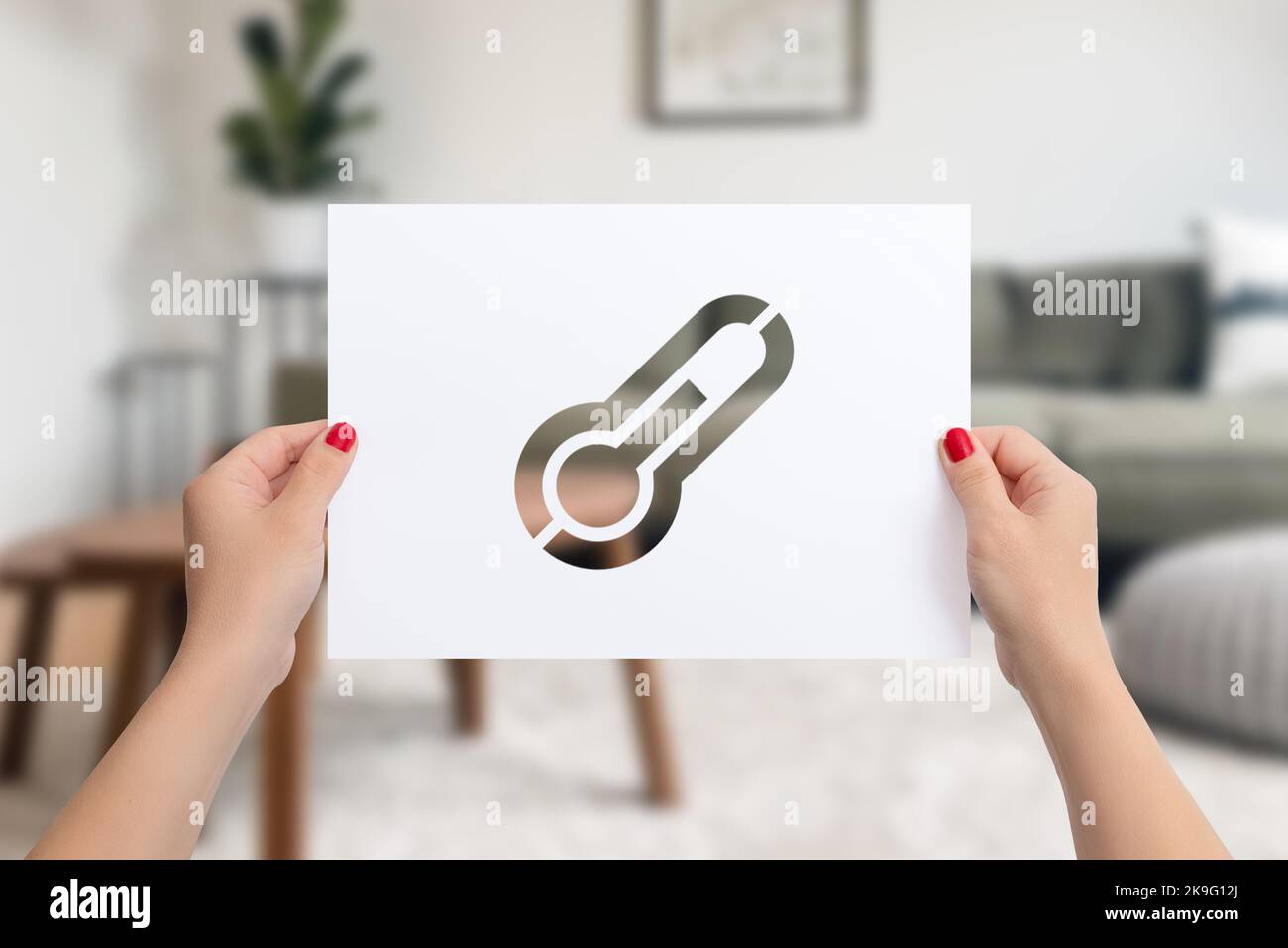 Paper in female hands with cutout thermometer. The concept of home heating in cold winter days Stock Photo